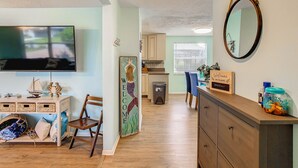 A living room with a TV, wooden furniture, a welcome sign, and a mirror. - 3/2 HEATED POOL HOME ON DEEP WATER CANAL (Crystal River)