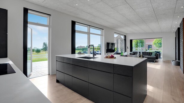 Une cuisine moderne dotée d’un grand îlot central, de grandes fenêtres et offrant une vue sur l’extérieur.