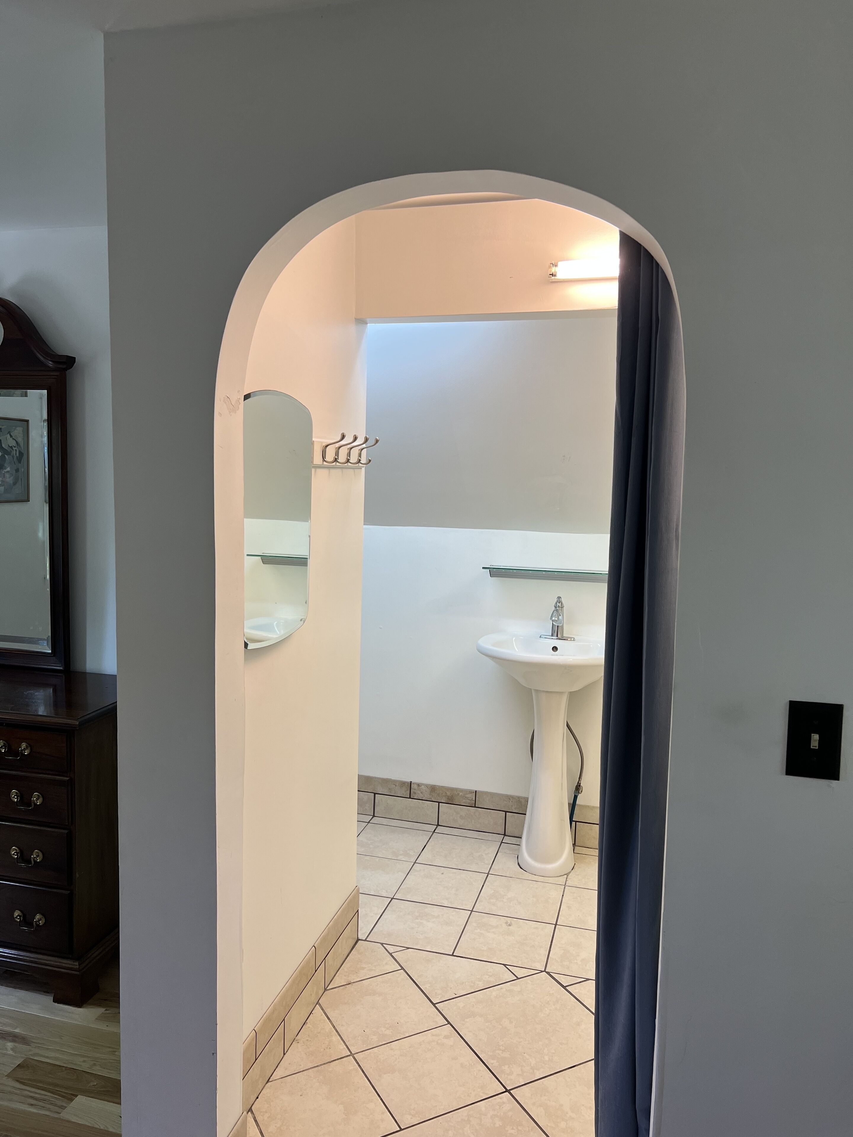 A bathroom with a white sink, a mirror, and a tiled floor.