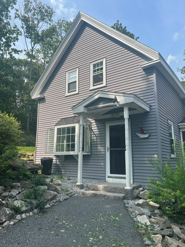 A two-story house with a covered porch, a front door, and two windows. - Boothbay Harbor, 2-Story Cottage, downtown (Boothbay Harbor)