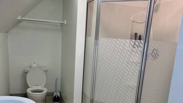 A bathroom with a toilet, a shower enclosure, and a sink.