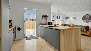 A modern kitchen with a central island, grey cabinetry, and a wooden floor.