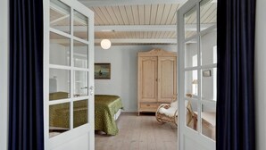 Una habitación con cama, armario, lámpara colgante y un cuadro en la pared.