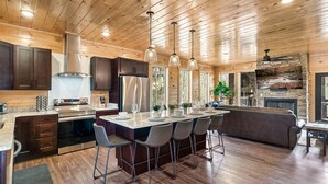 Una cucina moderna con soffitto in legno, elettrodomestici in acciaio inossidabile e un'isola centrale con sgabelli da bar.