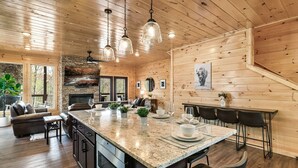 Cucina spaziosa con un'isola grande, pareti in legno e illuminazione a sospensione.