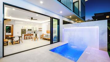 Uma casa moderna com uma sala de estar ampla, uma cozinha e uma pequena área de piscina ao ar livre.