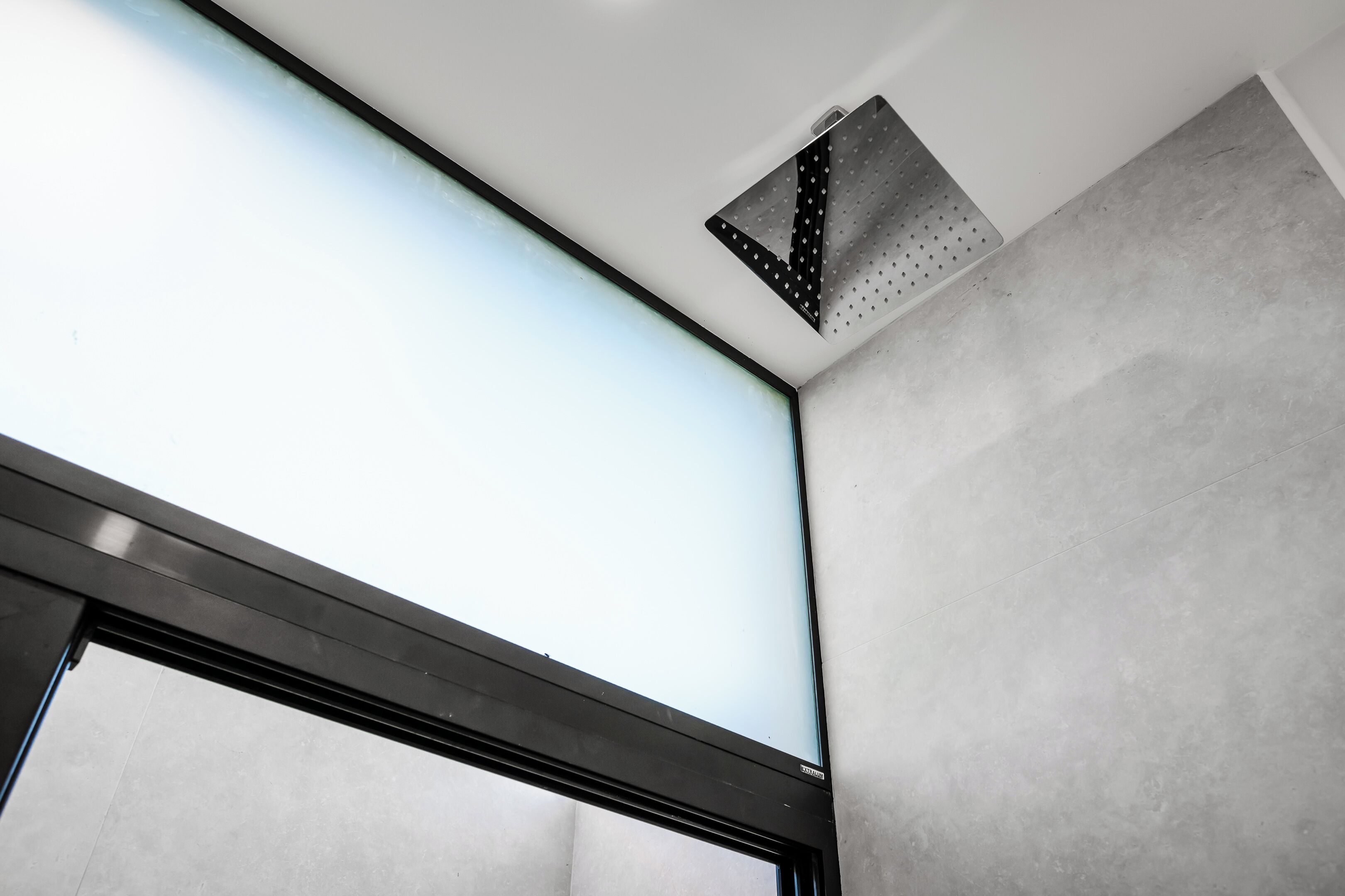 A ceiling with a recessed light fixture and a ventilation grille.