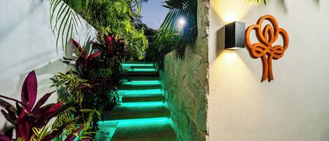 A staircase with green lighting, surrounded by lush tropical plants.