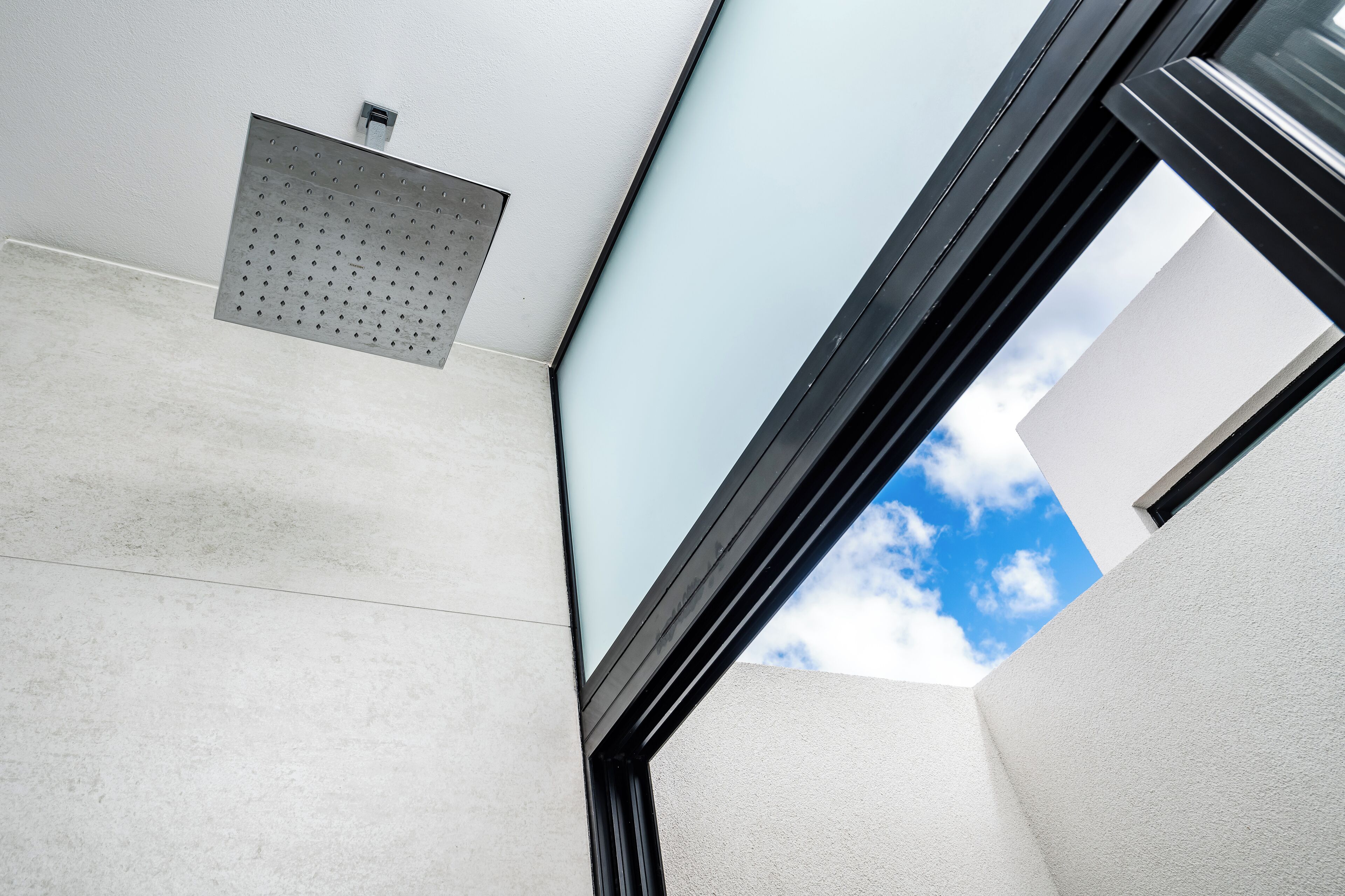 A corner view of a modern building with a metal vent and a window frame.