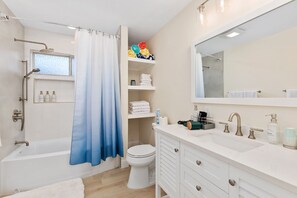 Ein modernes Badezimmer mit Badewanne, Toilette und Waschtisch mit großem Spiegel.