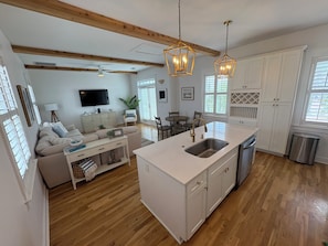 A modern kitchen with a central island, wooden beams, and pendant lighting.