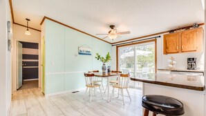 Una cocina con comedor, ventilador de techo, armarios de madera y vistas al exterior.
