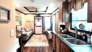 A compact kitchen with wooden cabinets, a built-in oven, and a sink. - Relaxing Getaway in the Texas Hill Country - Sweet Ginger Cottage (Canyon Lake)