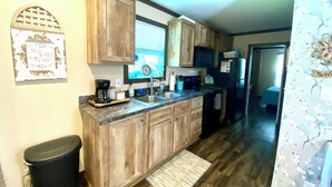 A kitchen with wooden cabinets, a stainless steel sink, a coffee maker, and a refrigerator. - Relaxing Getaway in the Texas Hill Country - Sweet Ginger Cottage (Canyon Lake)