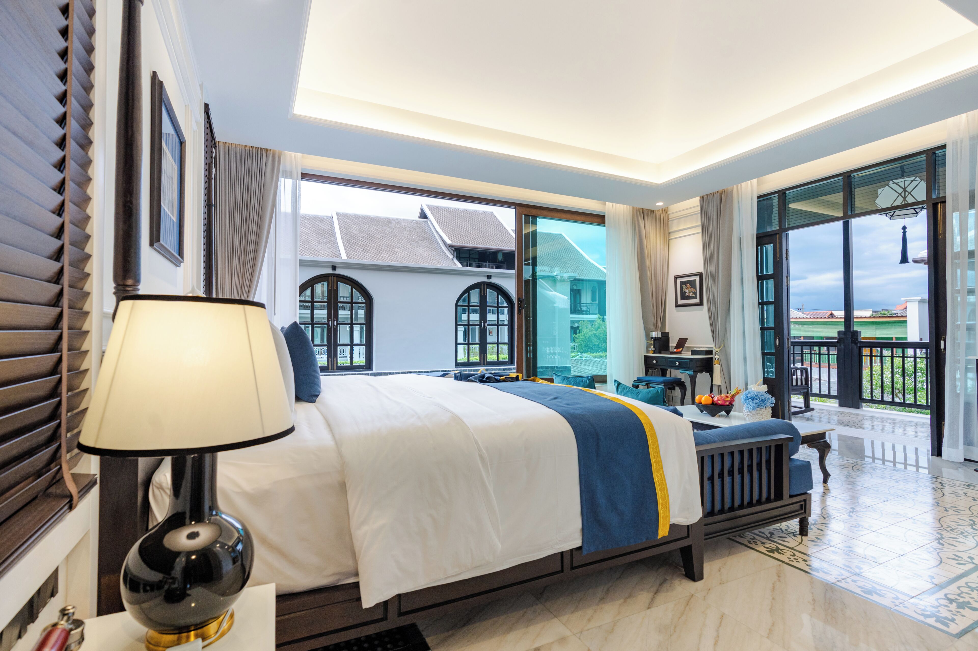 Een hotelkamer met een bed, een bureau, een stoel, een lamp en uitzicht.