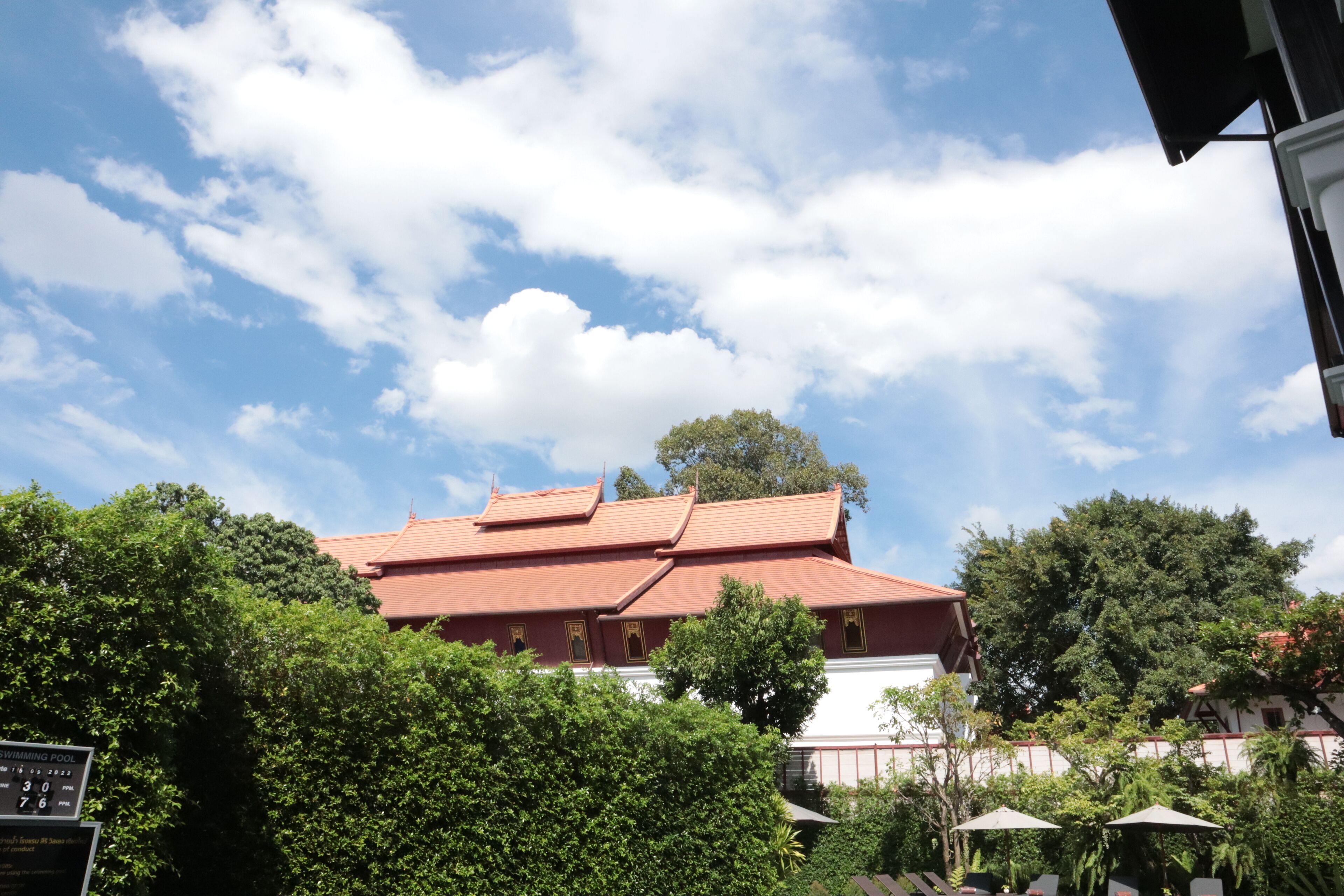 A traditional building with a red roof, surrounded by lush greenery and trees.
