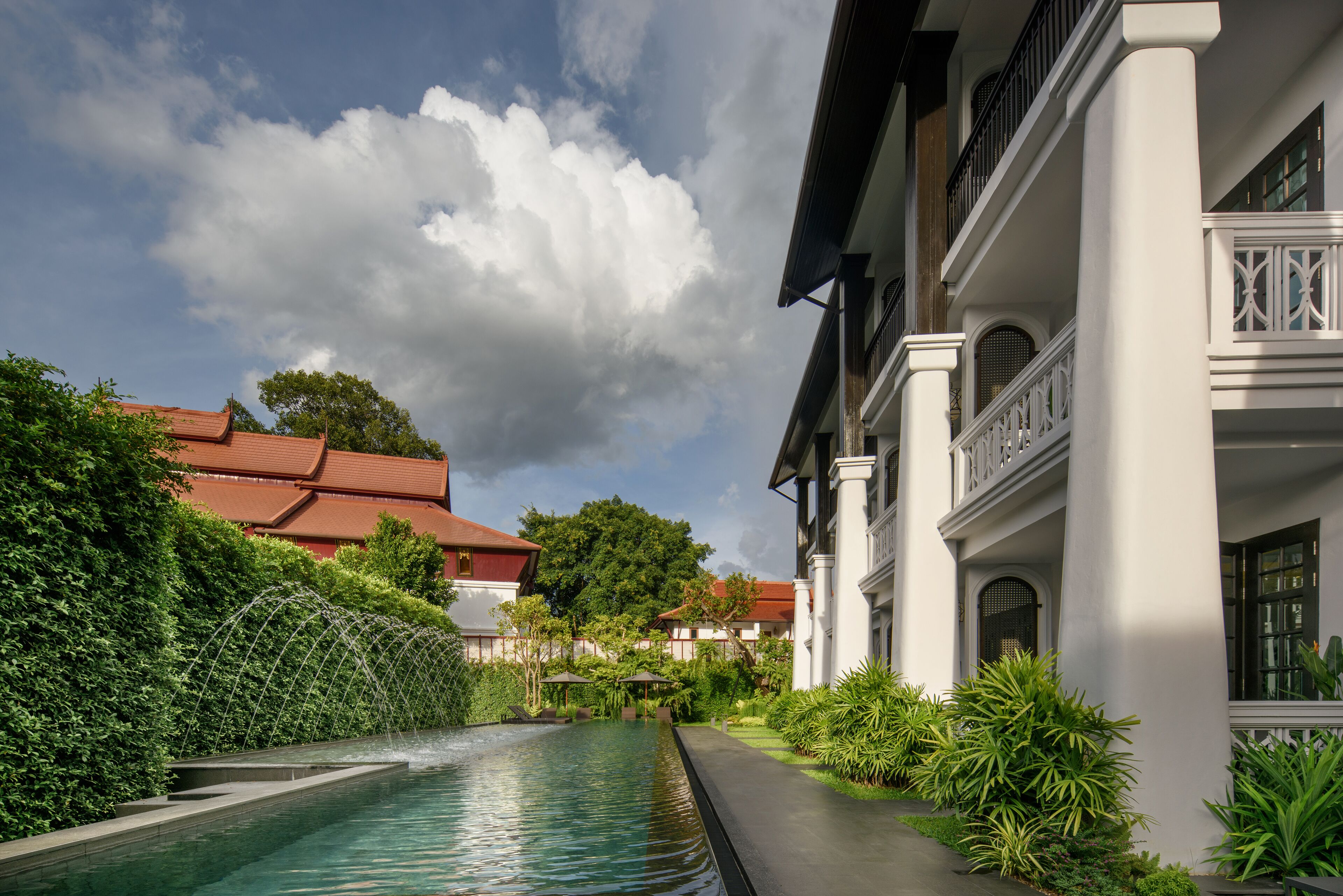 A swimming pool with a view of a building with a red roof and white columns.