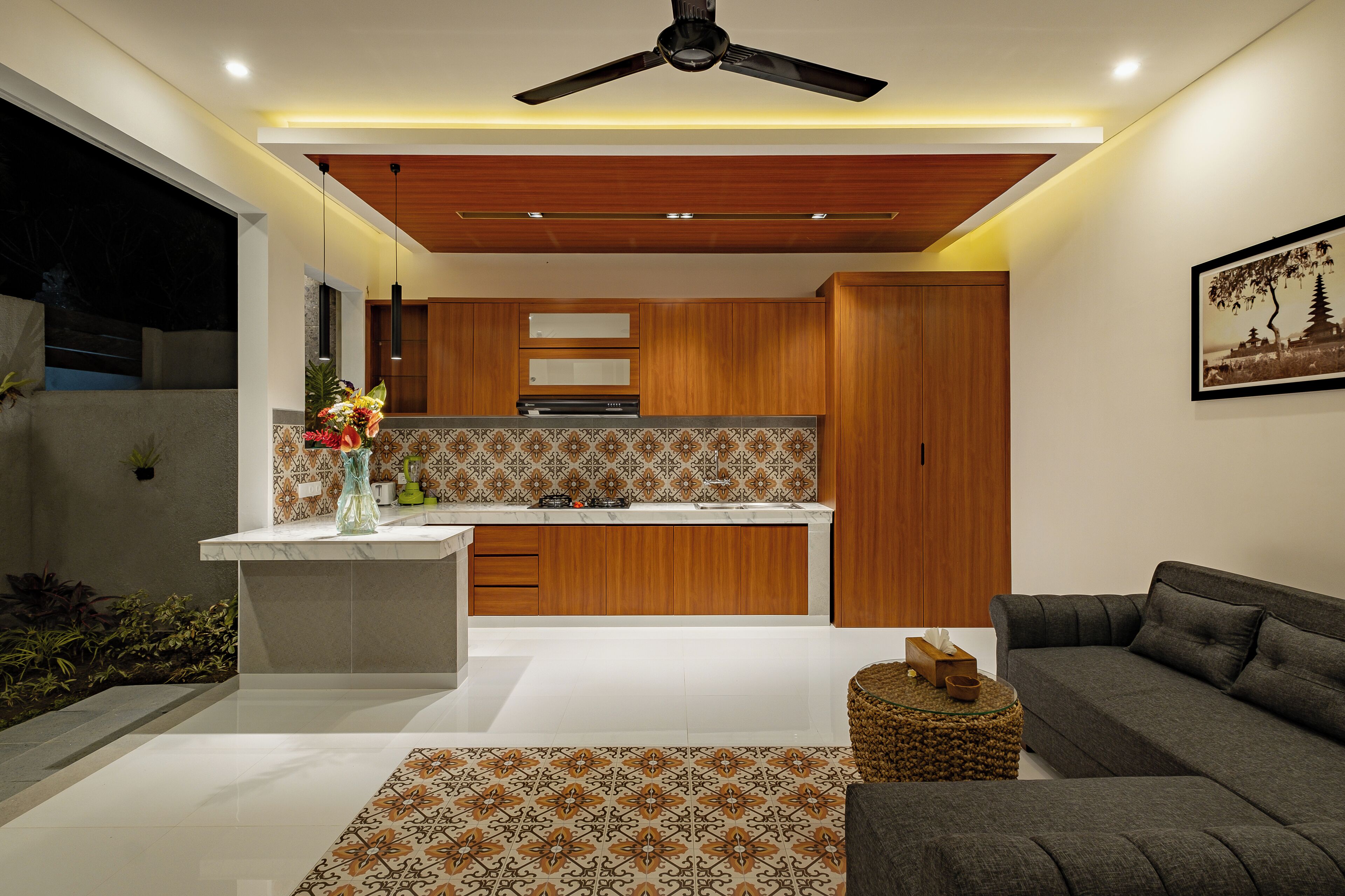 A modern kitchen with wooden cabinets, a marble countertop, and a ceiling fan.