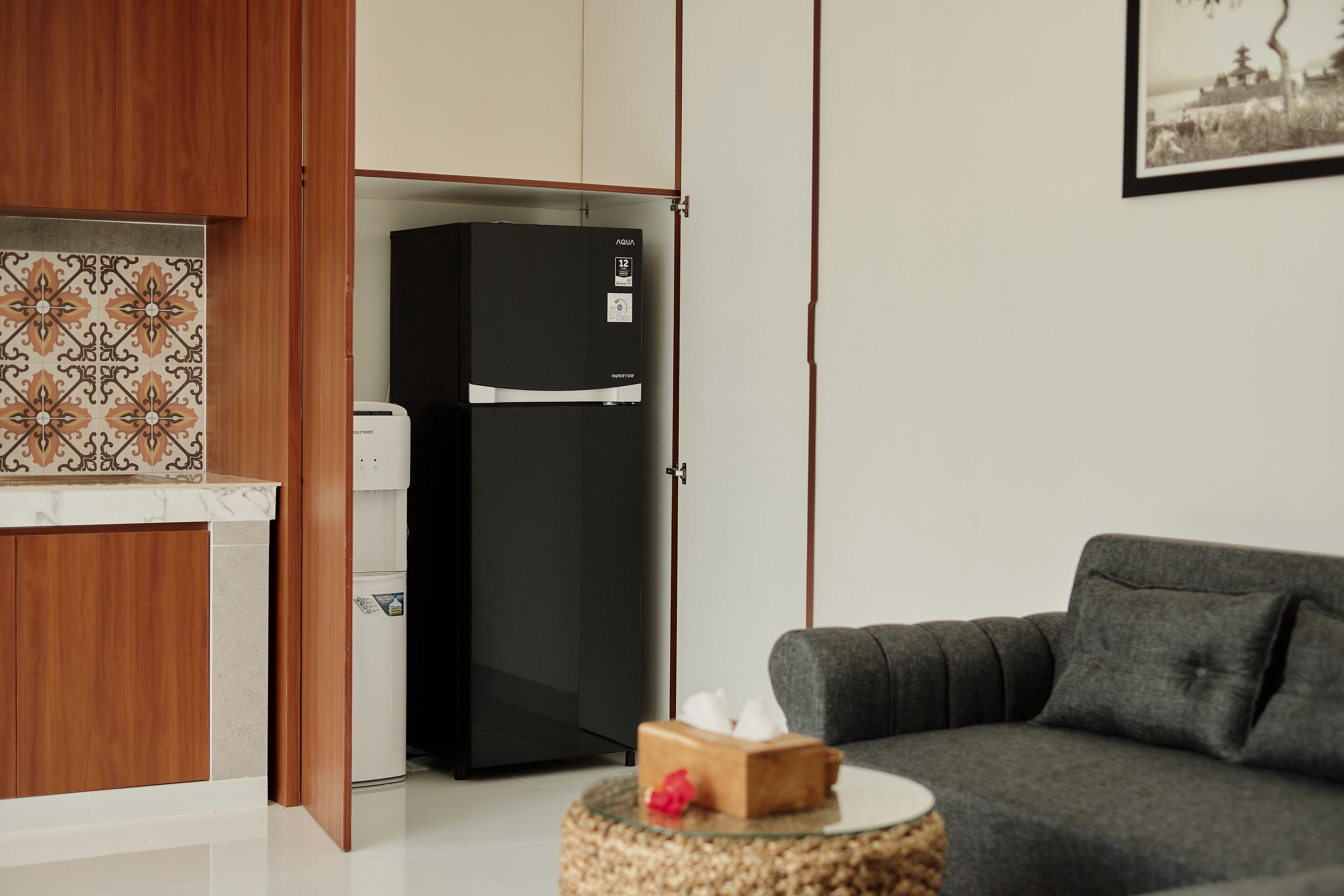 A modern kitchen with a black refrigerator, wooden cabinets, and a patterned backsplash.
