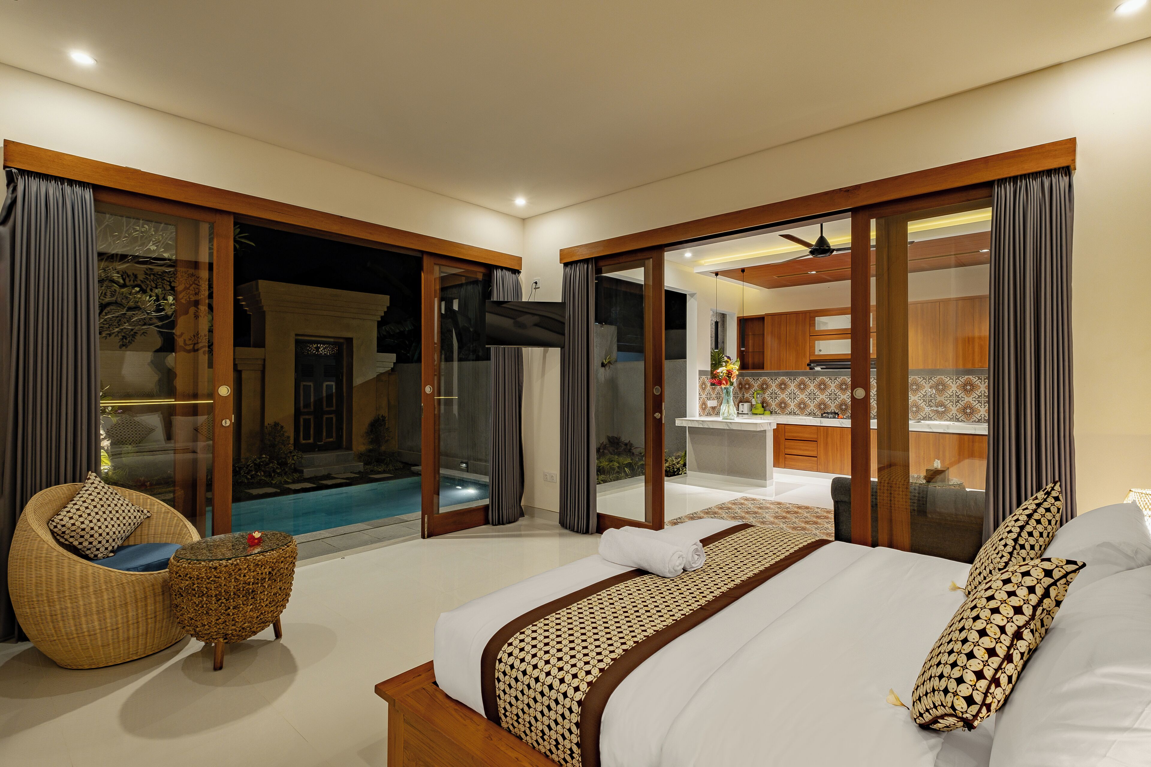 A modern hotel room with a large bed, a seating area, and a view of a swimming pool.