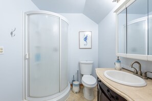 Bagno con doccia, toilette, lavandino e un quadro di un cavalluccio marino appeso alla parete.