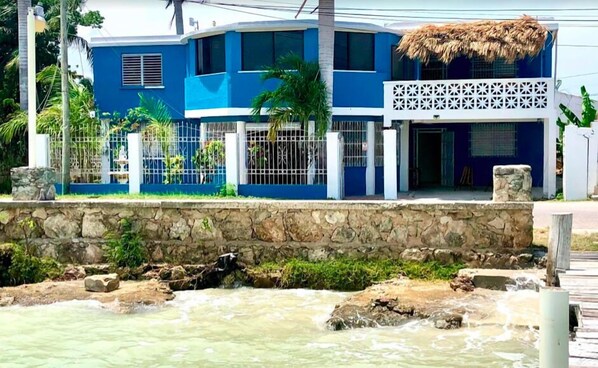 A two-story house with a blue exterior and a thatched roof. - Rum Punch Lodge (Corozal)