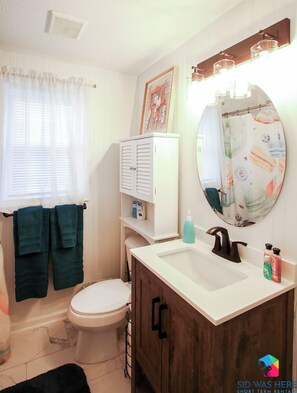 Un baño con inodoro, lavamanos, mueble y espejo.