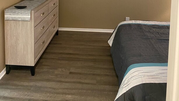 A bedroom with a bed, dresser, and mounted TV.