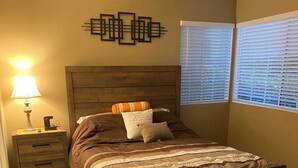 A bedroom with a wooden bed, a nightstand with a lamp, and a wall art piece. - Weekend Wine Getaway (Temecula)
