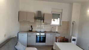 A compact kitchen with a built-in oven, a sink, and a window above the countertop. - Impeccable 2-Bed House in Privlaka, Croatia (Privlaka)