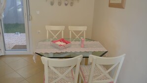 A dining area with a glass table, white chairs, and a pink baby carrier on the table.