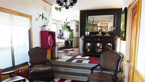 Una sala de estar con dos sillones, un sofá, un armario rojo y una escalera que lleva a otra habitación.