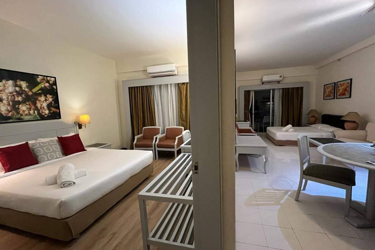 A hotel room with a bed, a desk, a chair, a sofa, and a dining table.