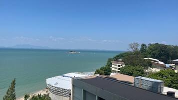 Une vue sur la côte, avec un bâtiment doté d’une terrasse sur le toit, un ciel dégagé et une ligne de côte lointaine.