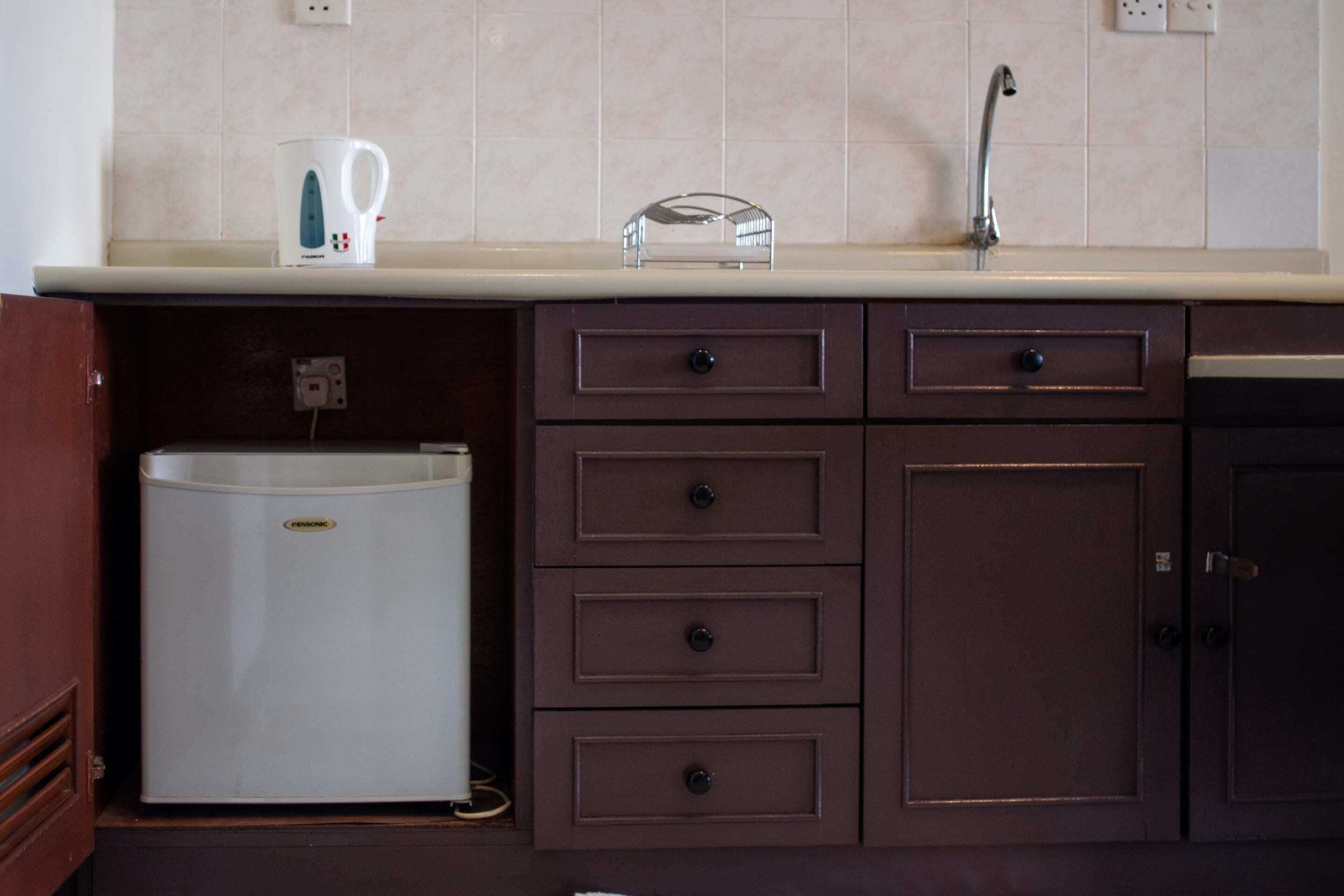 Una kitchenette con refrigerador, pileta y encimera.