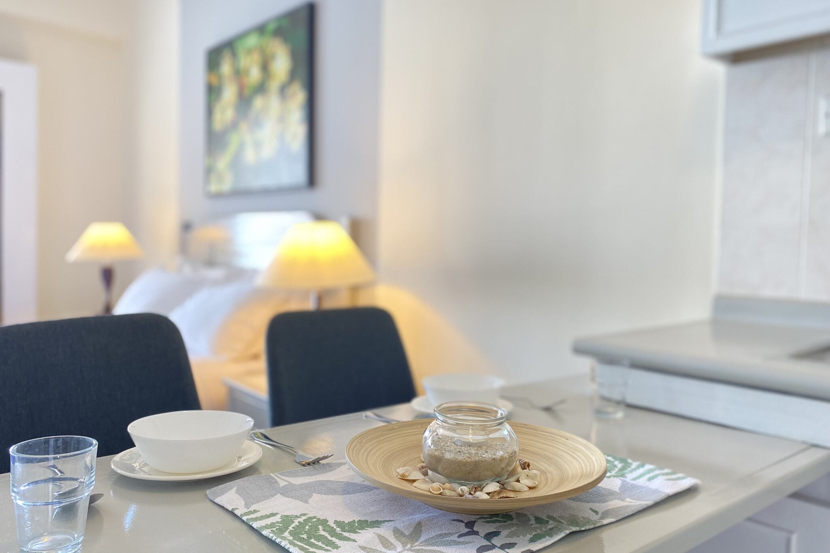 Een eettafel met een kom, een glas water, een pot voedsel en een bord met noten.