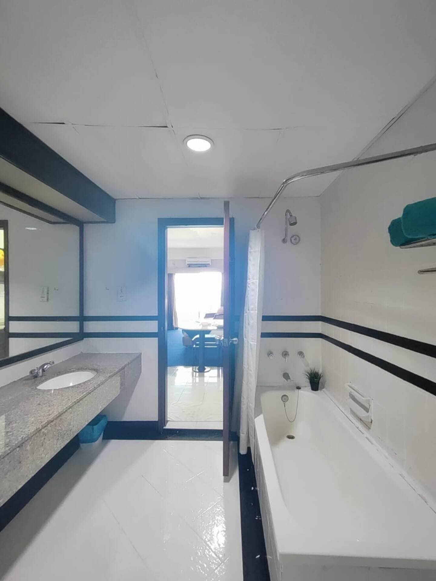 A bathroom with a sink, mirror, and shower area.