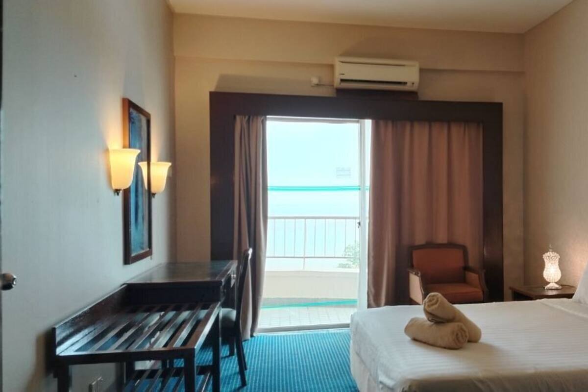 A hotel room with a bed, a desk, a chair, and a balcony.