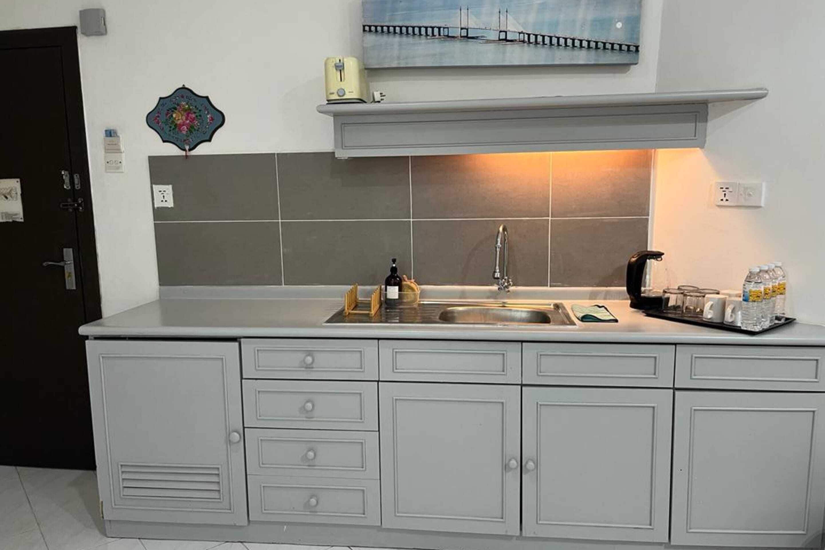 A kitchen with a grey countertop, a sink, and a painting above the counter.