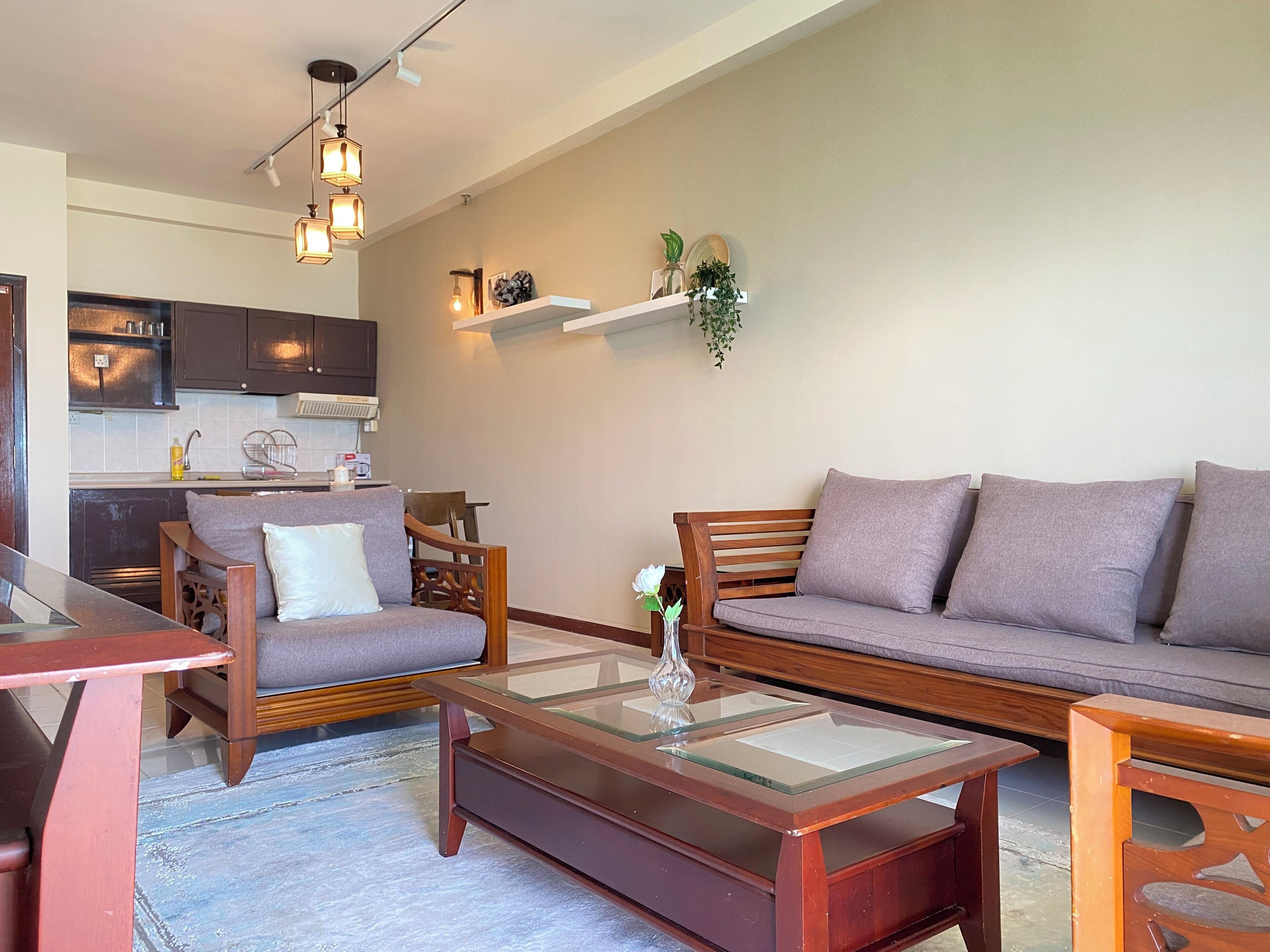 A living room with a sofa, armchairs, a coffee table, and a kitchen area in the background.