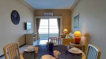 A dining area with a table set for four, a TV, and a window with curtains.