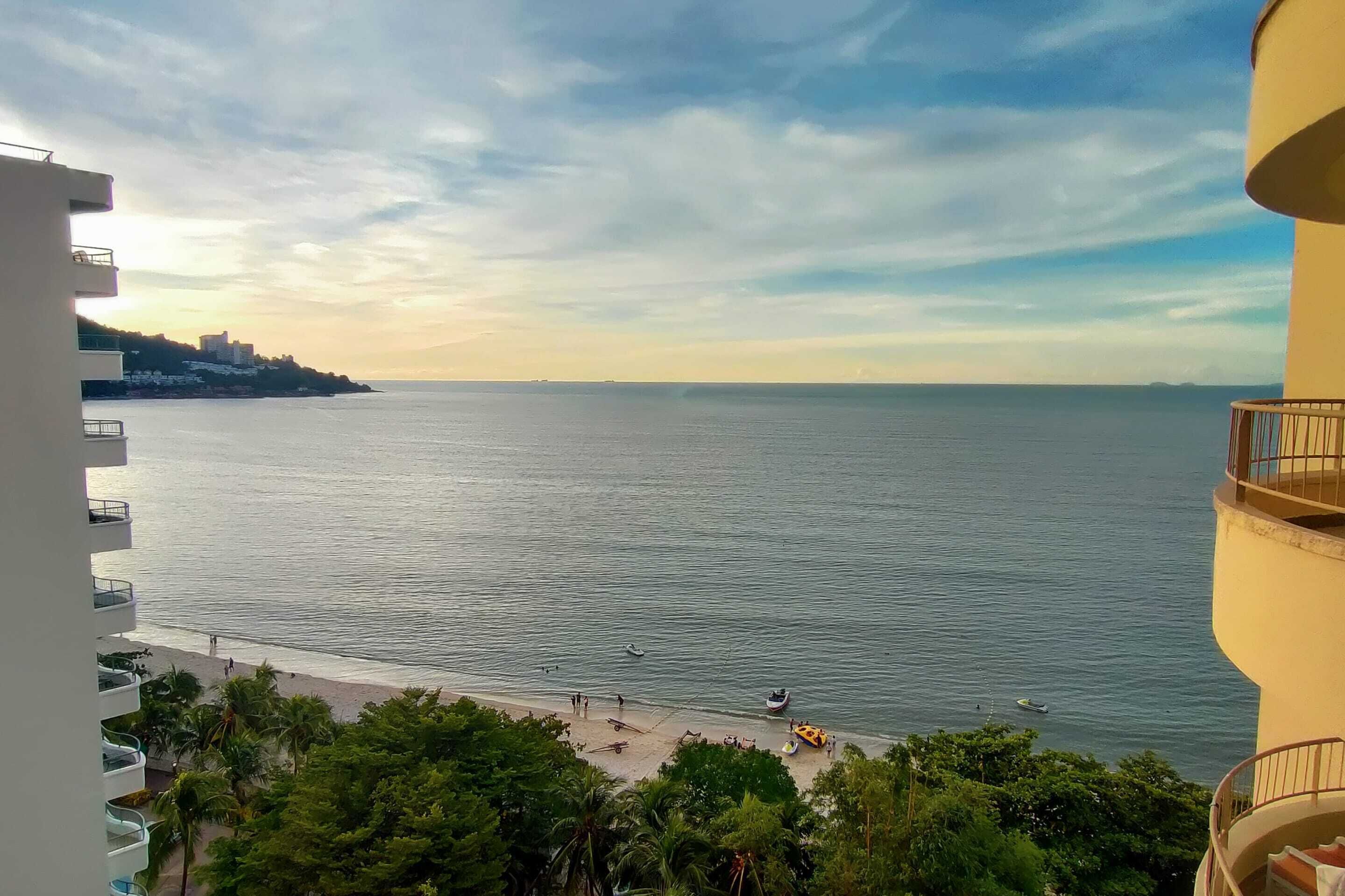 Vista costera con playa, océano y un edificio con balcones que dan al agua.