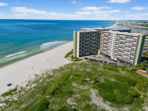 A beachfront hotel with multiple floors, a parking lot, and a view of the ocean. - Oceanfront, By 30A, Pool, Sauna, Boat Slips FREE! (Panama City Beach)