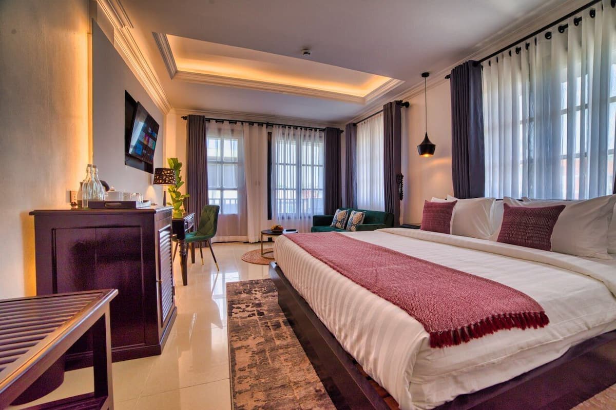 A modern hotel room with a large bed, a desk, a chair, and a TV.