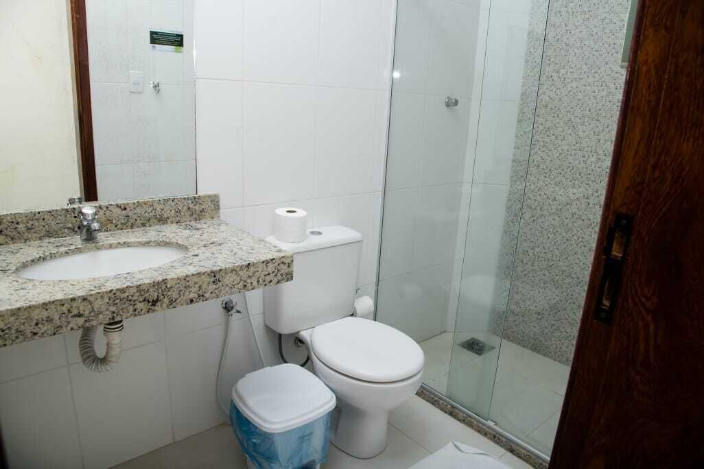 A bathroom with a granite sink, toilet, and a glass shower enclosure.