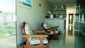 A reception area with wooden chairs and a reception desk. - Pousada Porto Prime (Sao Joao Da Barra)