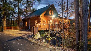 A log cabin with a porch, surrounded by trees and a paved driveway. - Free Dollywood Tix/VIEWS/Secluded/Couples/HotTub/ (Sevierville)