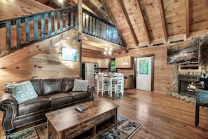 Un salón espacioso con una escalera de madera, una chimenea, un comedor y una cocina.