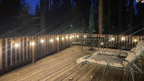 Eine Holzterrasse mit Gartenmöbeln und Lichterketten.