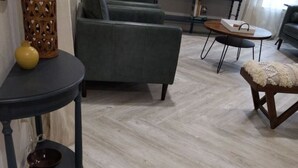 Ein Wohnzimmer mit grauem Sofa, einem runden Couchtisch und einer kleinen Holzbank.